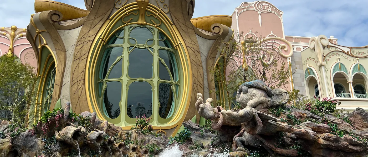 The ornate gold Art Nouveau facade of Peter Pan's Never Land Adventure at Fantasy Springs, Tokyo DisneySea, with a rockwork waterfall in front